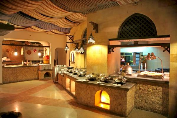 Innenansicht des Restaurants im PickAlbatros Oasis Port Ghalib Hotel mit Steinwänden und beleuchteten Kochstationen.