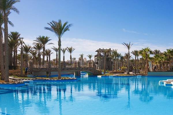 Ein Swimmingpool im PickAlbatros Oasis Port Ghalib Hotel mit Palmen und einer Brücke im Hintergrund.