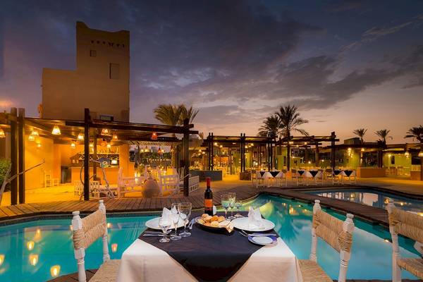 PickAlbatros Oasis Port Ghalib - Außenbereich am Pool bei Nacht mit beleuchteten Tischen und Stühlen.