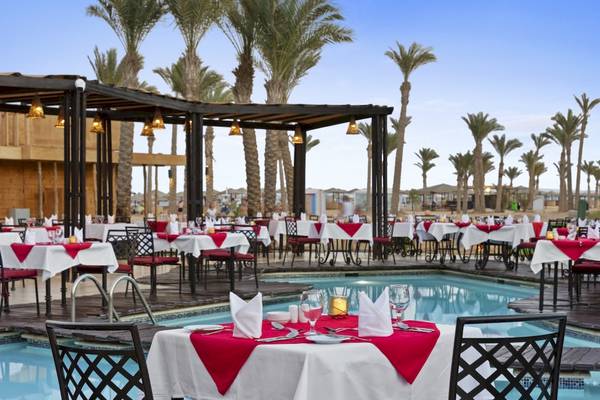 Poolseite des PickAlbatros Oasis Port Ghalib Hotels mit gedeckten Tischen im Freien.