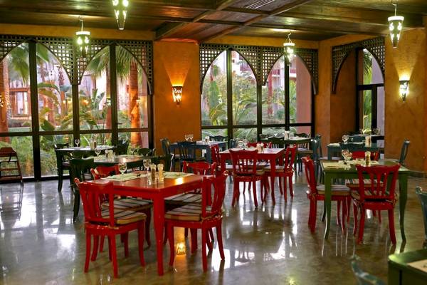 Innenansicht des Restaurants im Pick Albatros Oasis Port Ghalib Hotel mit roten Tischen und Stühlen.