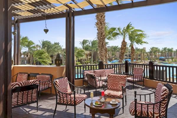 Terrasse des PickAlbatros Oasis Port Ghalib Hotels mit gepolsterten Stühlen, Tischen und Blick auf den Pool.