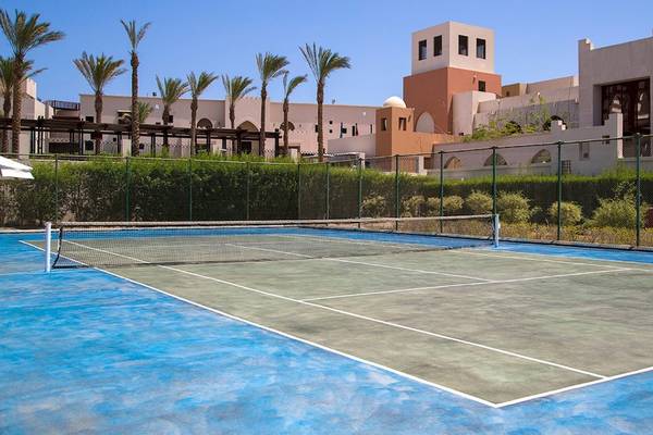 Tennisplatz vor dem Hotel PickAlbatros Sands Port Ghalib mit Gebäuden im Hintergrund.