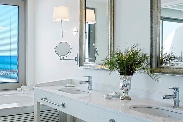 Badezimmer des Knossos Beach Bungalows Suites Resort & Spa mit Meerblick, Badewanne, zwei Waschbecken und Spiegeln.