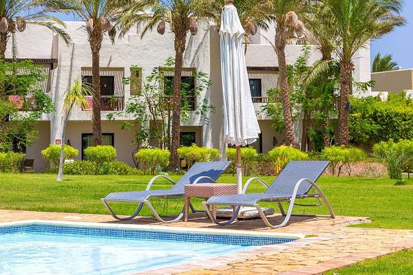 Pool mit Liegestühlen und Sonnenschirm vor einem Hotel