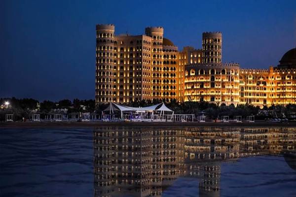 Al Hamra Residenz bei Nacht, beleuchtet und reflektiert im Wasser.
