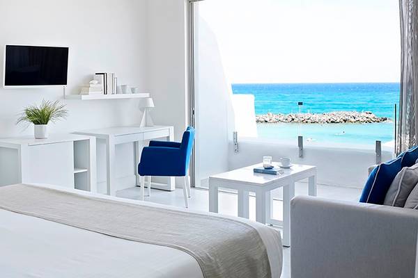 Innenansicht eines Zimmers im Knossos Beach Bungalows Suites Resort & Spa mit Blick auf das Meer.