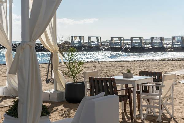 Sitzbereich am Strand mit Tischen und Stühlen im Knossos Beach Bungalows Suites Resort & Spa