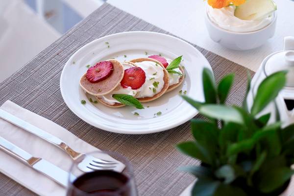 Frühstücksbuffet im Knossos Beach Bungalows Suites Resort & Spa mit Pfannkuchen, Früchten und Kaffee.