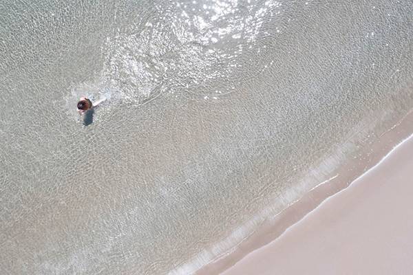 Zwei Personen stehen im klaren Wasser am Strand.