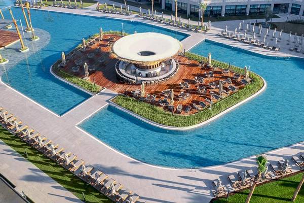 Luftaufnahme des Poolbereichs des Lago Hotels mit Sonnenliegen und Schirmen.