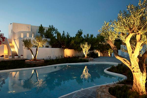Poolbereich des Knossos Beach Bungalows Suites Resort & Spa bei Nacht, beleuchtet und mit Bäumen umgeben.