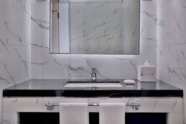 Badezimmer im Marriott Resort Palm Jumeirah, Dubai, mit Marmorwänden und schwarzen Marmortischplatte.