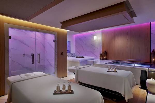 Spa-Behandlungsraum im Marriott Resort Palm Jumeirah, Dubai, mit zwei Behandlungstischen und einem Whirlpool.