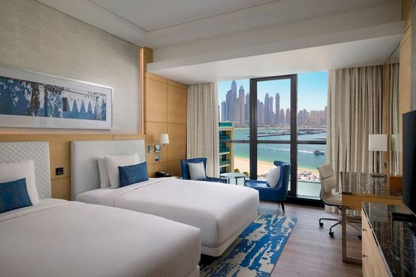 Zwei Betten im Marriott Resort Palm Jumeirah, Dubai, mit Blick auf die Stadt und das Meer.