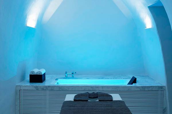 Badezimmer im Knossos Beach Bungalows Suites Resort & Spa mit Badewanne und Massageliege.