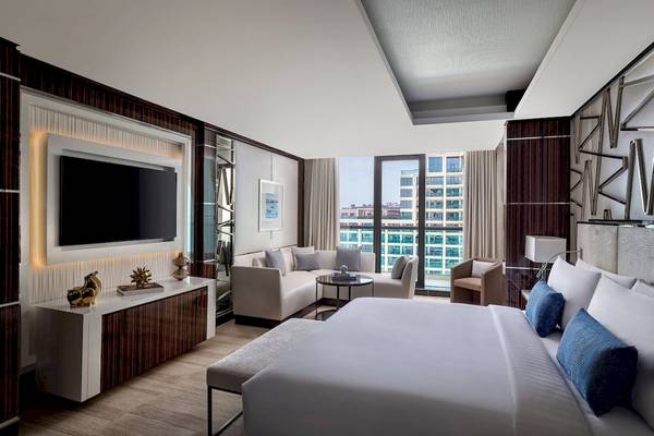 Innenansicht eines Schlafzimmers im Marriott Resort Palm Jumeirah Hotel in Dubai mit Fernseher, Sofa und Aussicht auf das Meer.