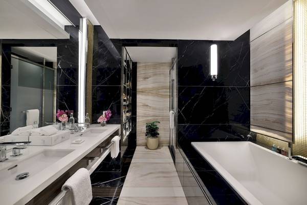 Badezimmer im Marriott Resort Palm Jumeirah, Dubai, mit schwarzen Marmorwänden und weißen Oberflächen.