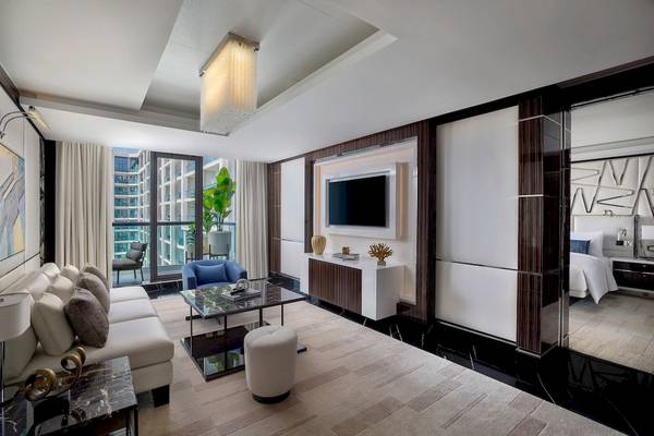 Wohnzimmer im Marriott Resort Palm Jumeirah mit moderner Einrichtung, Couch, Tisch, Fernseher und Blick auf die Stadt.