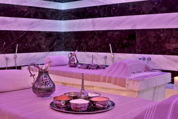 Spa-Behandlungsraum im Marriott Resort Palm Jumeirah in Dubai mit Marmorwänden, einem Bett, Kerzen, und verschiedenen Behandlungsutensilien.