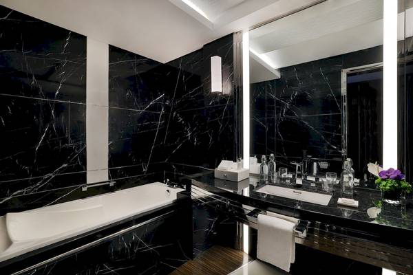 Schwarzes Marmorbadezimmer im Marriott Resort Palm Jumeirah, Dubai, mit Badewanne, Waschbecken und Spiegel.