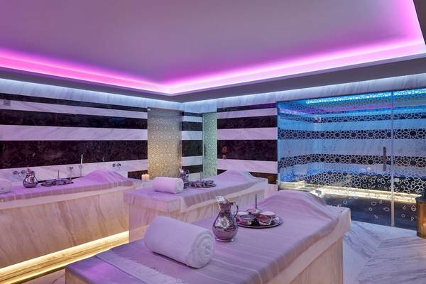 Spa-Behandlungsraum im Marriott Resort Palm Jumeirah, Dubai mit Marmorwänden und violetten Lichtern.