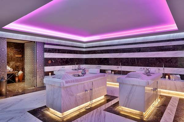 Spa-Bereich im Marriott Resort Palm Jumeirah, Dubai mit Marmorwänden, violetter Beleuchtung und zwei Badewannen.
