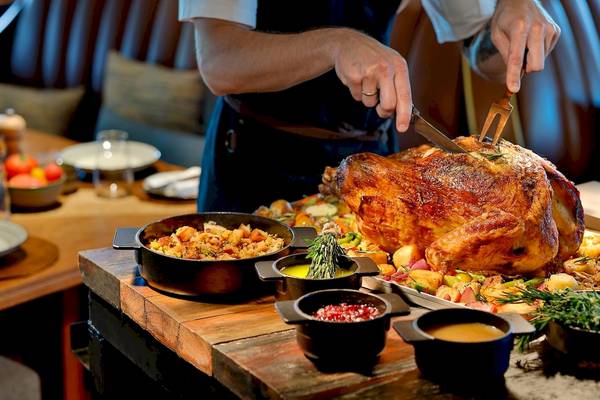 Ein Kellner serviert ein festliches Weihnachtsessen im Marriott Resort Palm Jumeirah, Dubai, mit einem großen Truthahn und Beilagen.