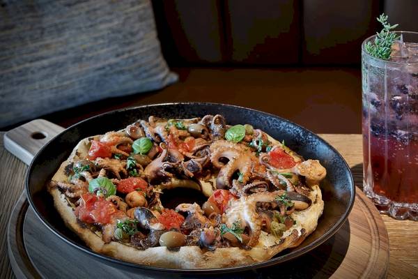 Oktopus-Pizza auf einem Teller mit einem Getränk im Marriott Resort Palm Jumeirah