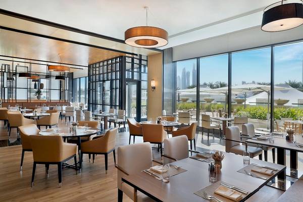 Innenansicht des Restaurants im Marriott Resort Palm Jumeirah, Dubai, mit großen Fenstern und Blick auf die Stadt.