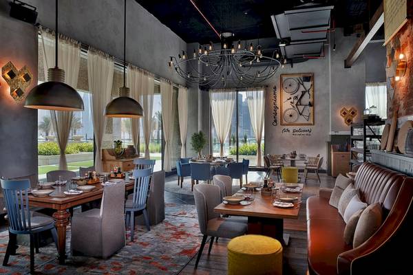 Innenansicht des Marriott Resort Palm Jumeirah in Dubai mit Esstischen und Stühlen, Kronleuchtern und Wanddekorationen.