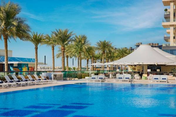 Außenpoolbereich des Marriott Resort Palm Jumeirah in Dubai mit weißen Sonnenliegen und großen weißen Sonnenschirmen.
