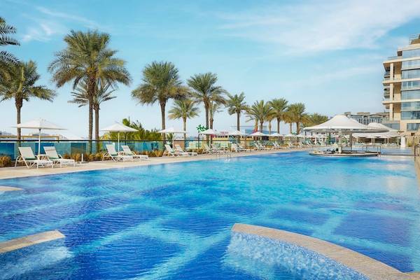 Außenpoolbereich des Marriott Resort Palm Jumeirah in Dubai mit Sonnenliegen und Sonnenschirmen.