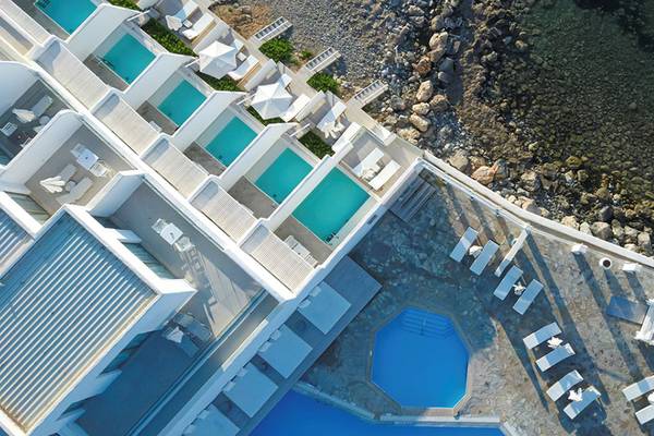 Oberansicht des Knossos Beach Bungalows Suites Resort & Spa mit Swimmingpools und Liegestühlen.