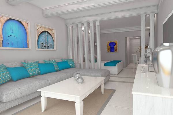 Wohnzimmer im Grand Palace Hotel mit grauem Sofa, blauen Kissen, weißem Tisch und Marmorboden.