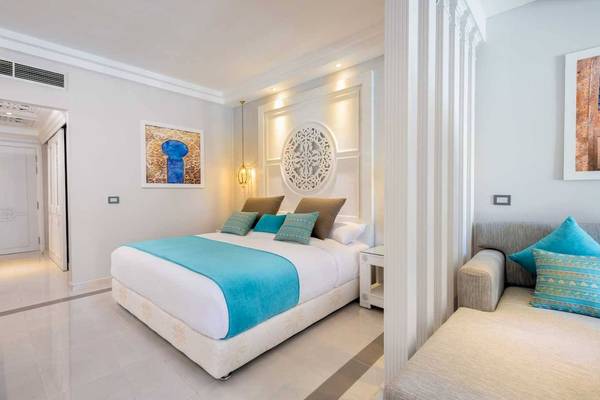 Innenansicht des Schlafzimmers im Grand Palace Hotel mit einem großen Bett und zwei Sofas.