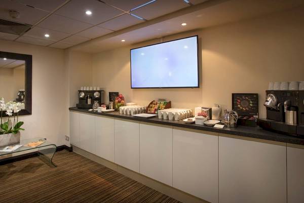 Frühstücksraum im Tower Hotel, London mit Fernseher, Kaffeemaschine und Frühstücksauswahl.