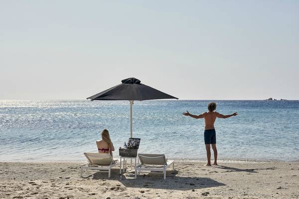 Mann und Frau am Strand unter einem Sonnenschirm mit Blick auf das Meer, Archipelagos Hotel.