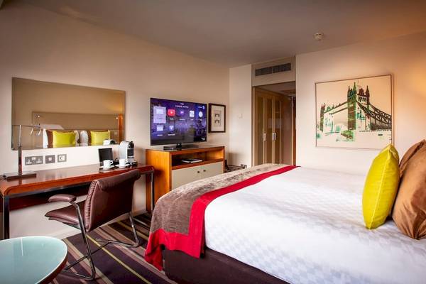 Hotelzimmer im Tower Hotel, London mit Bett, Schreibtisch, Fernseher und Dekoration.