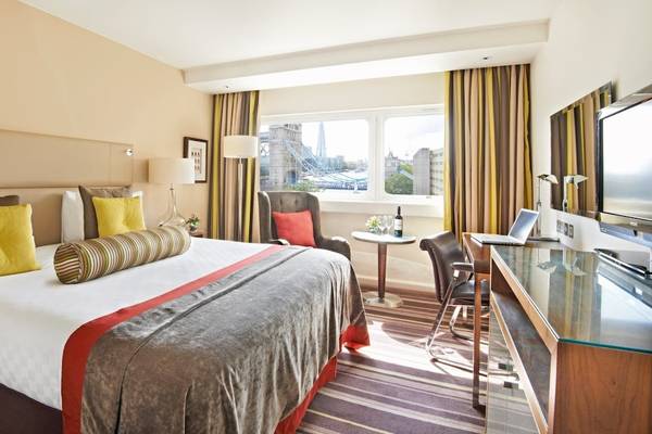 Das Tower Hotel Zimmer mit Bett, Blick auf London Tower und Möbeln.