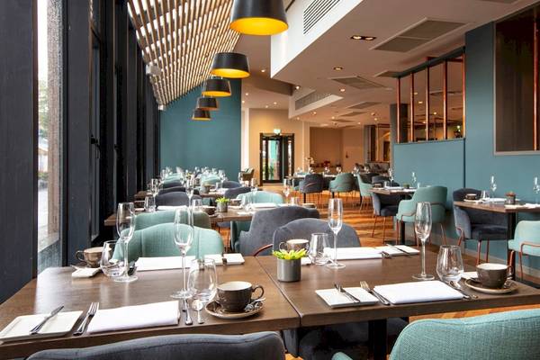 Innenansicht des Restaurants im Tower Hotel in London mit blauen Wänden, Holzböden und modernen Möbeln.