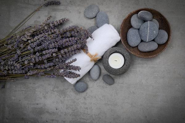 Lavendel, Handtuch, Kerze und Steine auf Beton