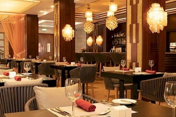 Innenansicht des Restaurants im Savoy Seychelles Resort & Spa mit gedeckten Tischen, Stühlen und Kronleuchtern.