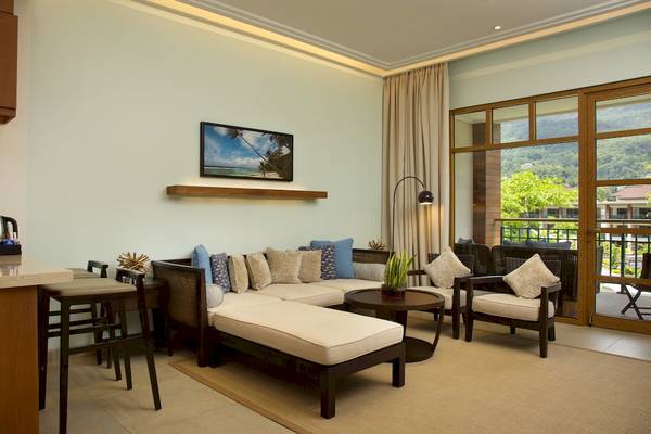 Wohnbereich im Savoy Seychelles Resort & Spa mit modernem Design, großen Fenstern und Blick auf die Berge.