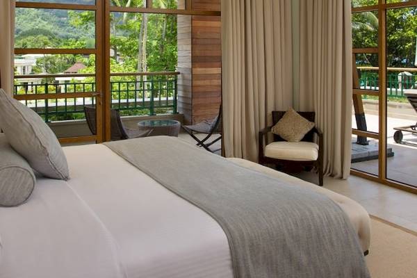 Schlafzimmer im Savoy Seychelles Resort & Spa mit großem Bett und Balkon mit Blick auf den Dschungel.