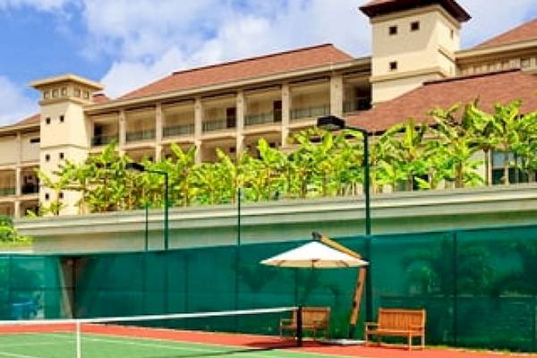 Tennisplatz im Savoy Seychelles Resort & Spa mit einem weißen Schirm und zwei Bänken.