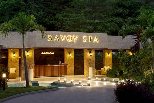 Außenansicht des Savoy Seychelles Resort & Spa mit beleuchteter Fassade und Garten.