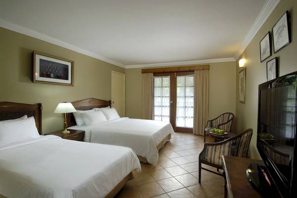 Doppelzimmer im Berjaya Beau Vallon Bay Resort & Casino mit zwei Betten und einem Fernseher.
