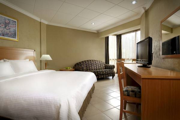Hotelzimmer im Berjaya Beau Vallon Bay Resort & Casino mit Bett, Sofa, Schreibtisch und Fernseher