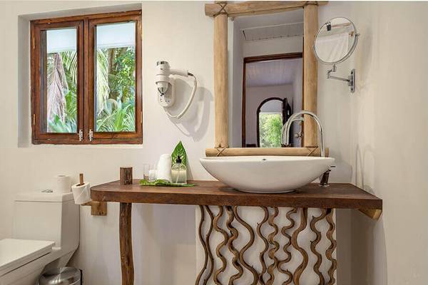 Ein Badezimmer im Bliss Hotel Praslin mit einem Waschbecken, Spiegel und Fenster.